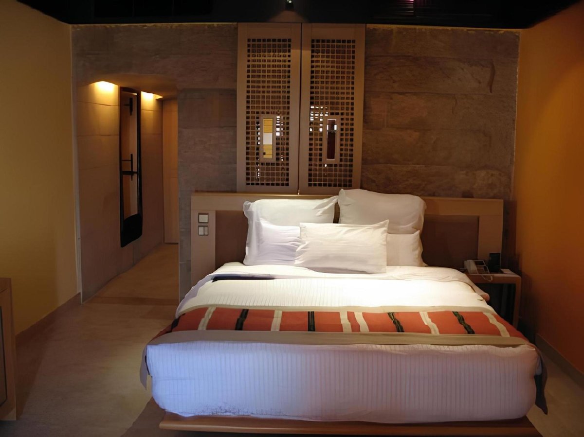 Retac Qunay Dahab Resort & Spa guest room with a large bed and stone walls.