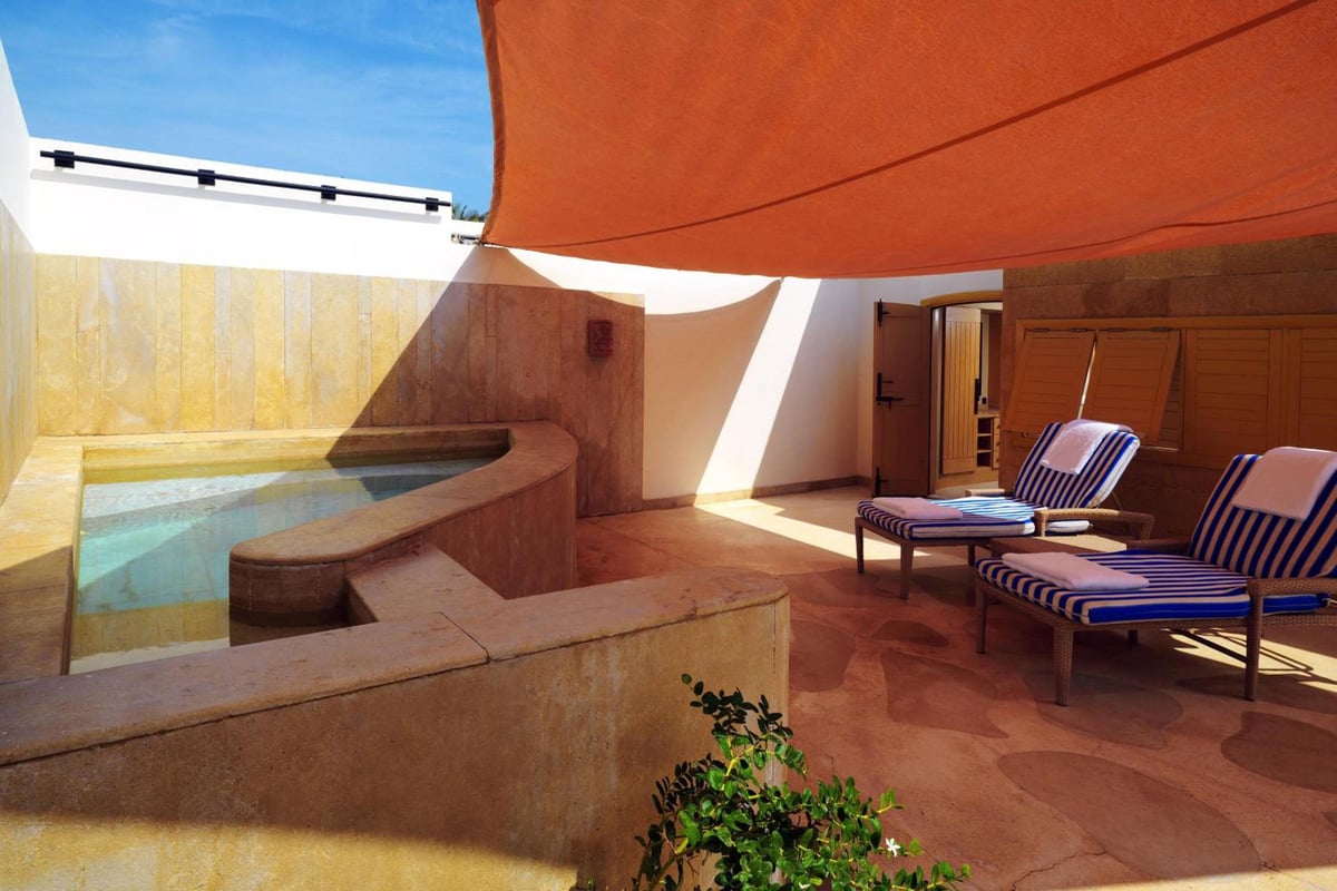 Retac Qunay Dahab Resort & Spa terrace with a plunge pool and striped lounge chairs.