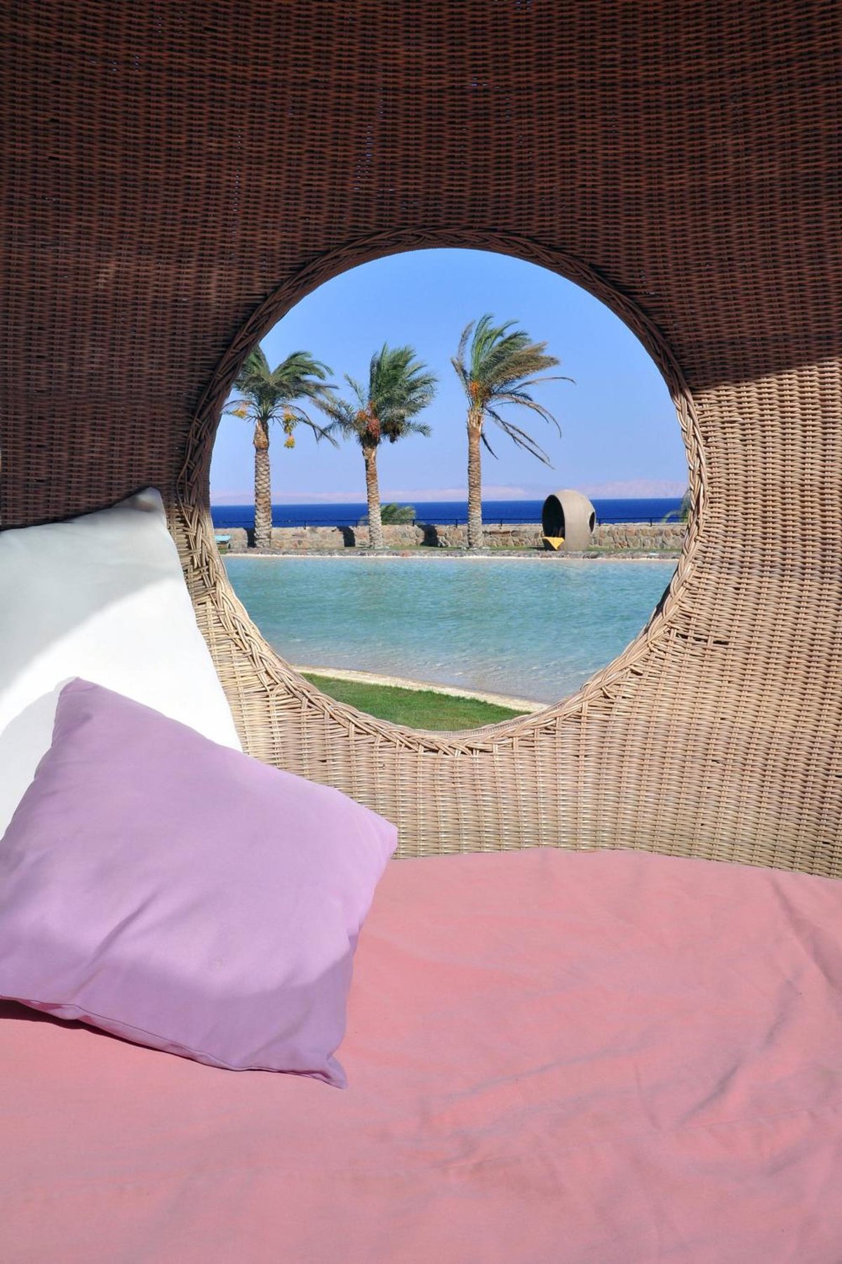 Retac Qunay Dahab Resort & Spa daybed with a round wicker frame and sea view.
