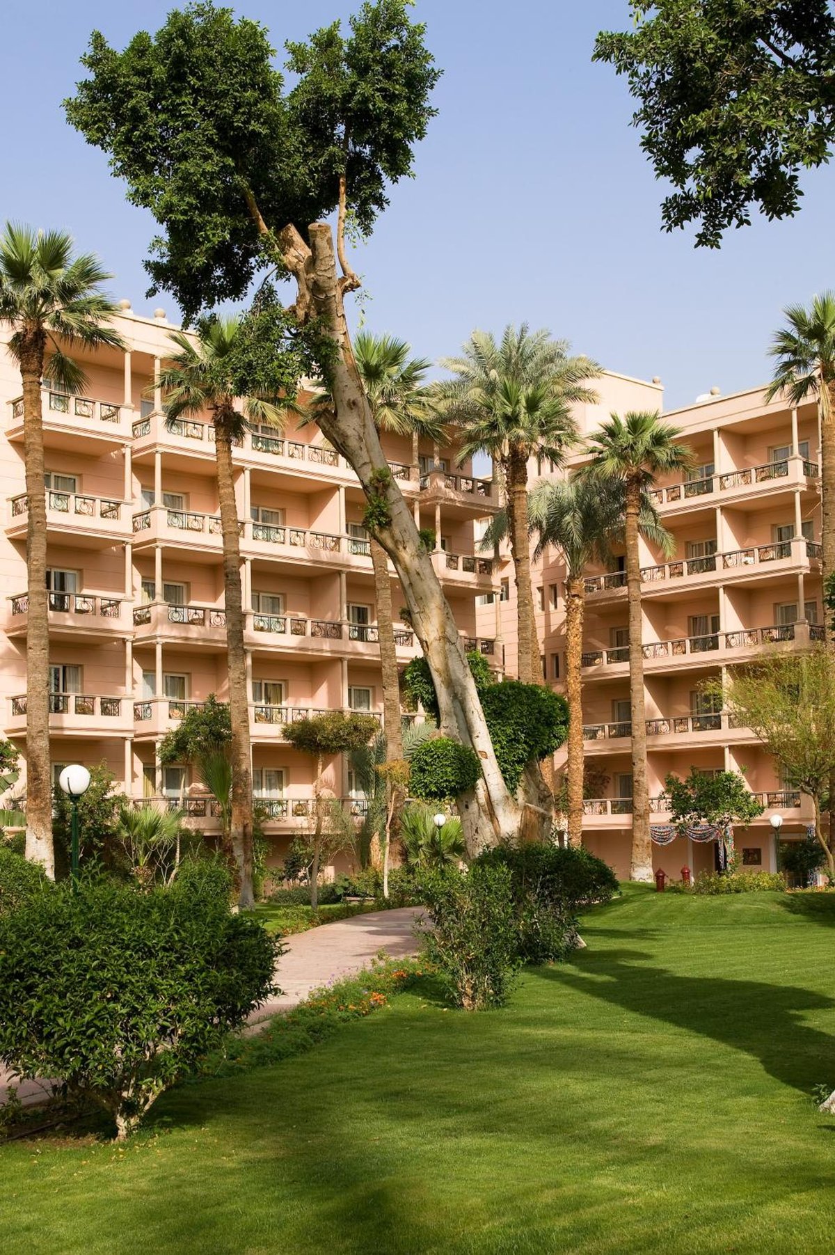 Pavillon Winter Luxor garden courtyard with a green lawn and balconies.