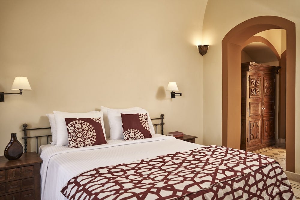 Dawar El Omda Hotel El Gouna (Adults Only) bedroom with a patterned bedspread and carved wooden door.