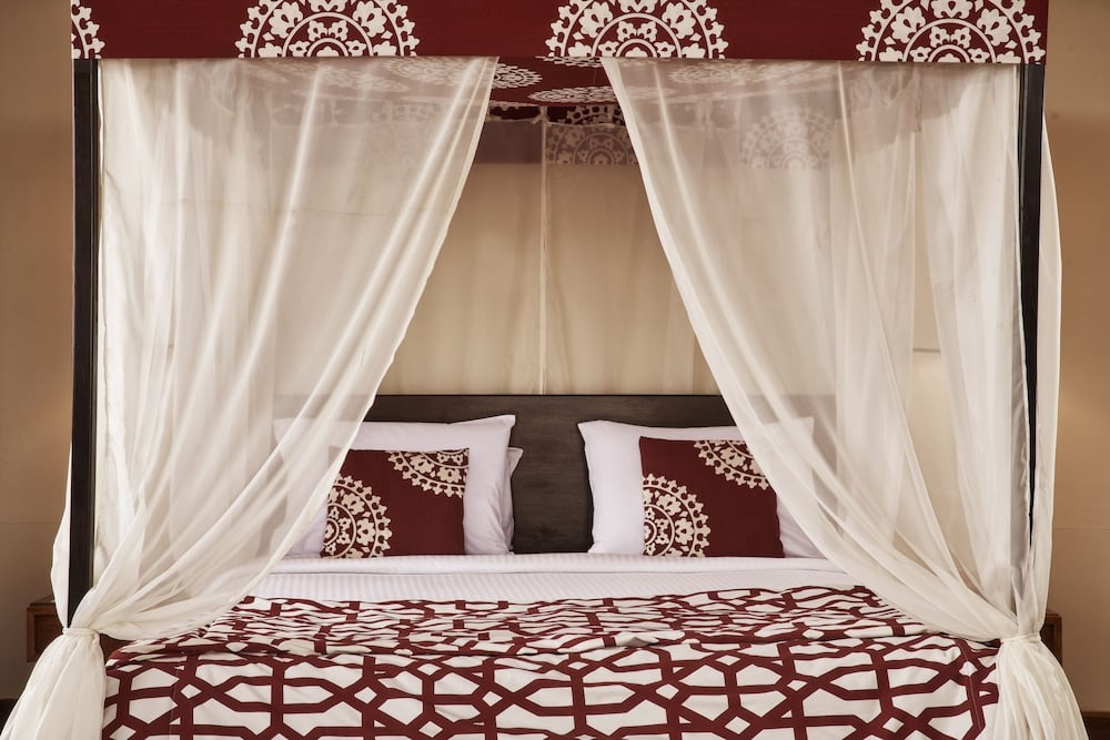 Dawar El Omda Hotel El Gouna (Adults Only) bedroom with sheer canopy curtains and patterned bedding.