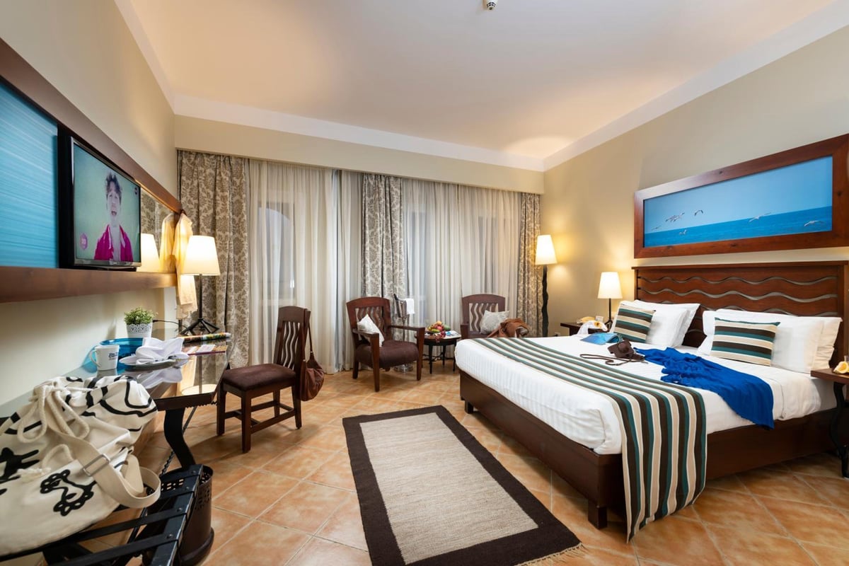 Three Corners Ocean View El Gouna (Adults Only) guest room with striped bedding and a seating area.