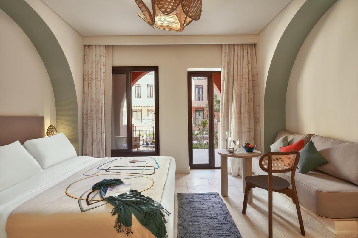 Three Corners Ocean View El Gouna (Adults Only) bedroom with arched walls and balcony doors.