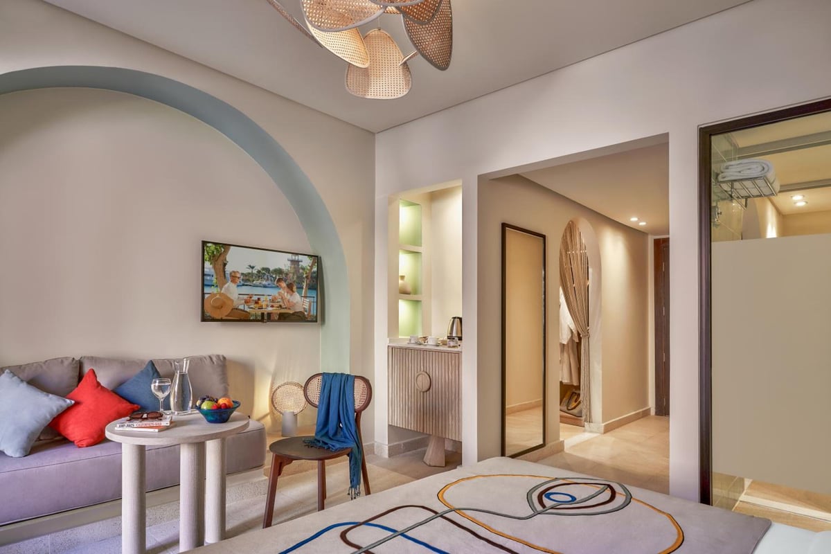 Three Corners Ocean View El Gouna (Adults Only) sitting area with a curved sofa and wall-mounted TV.