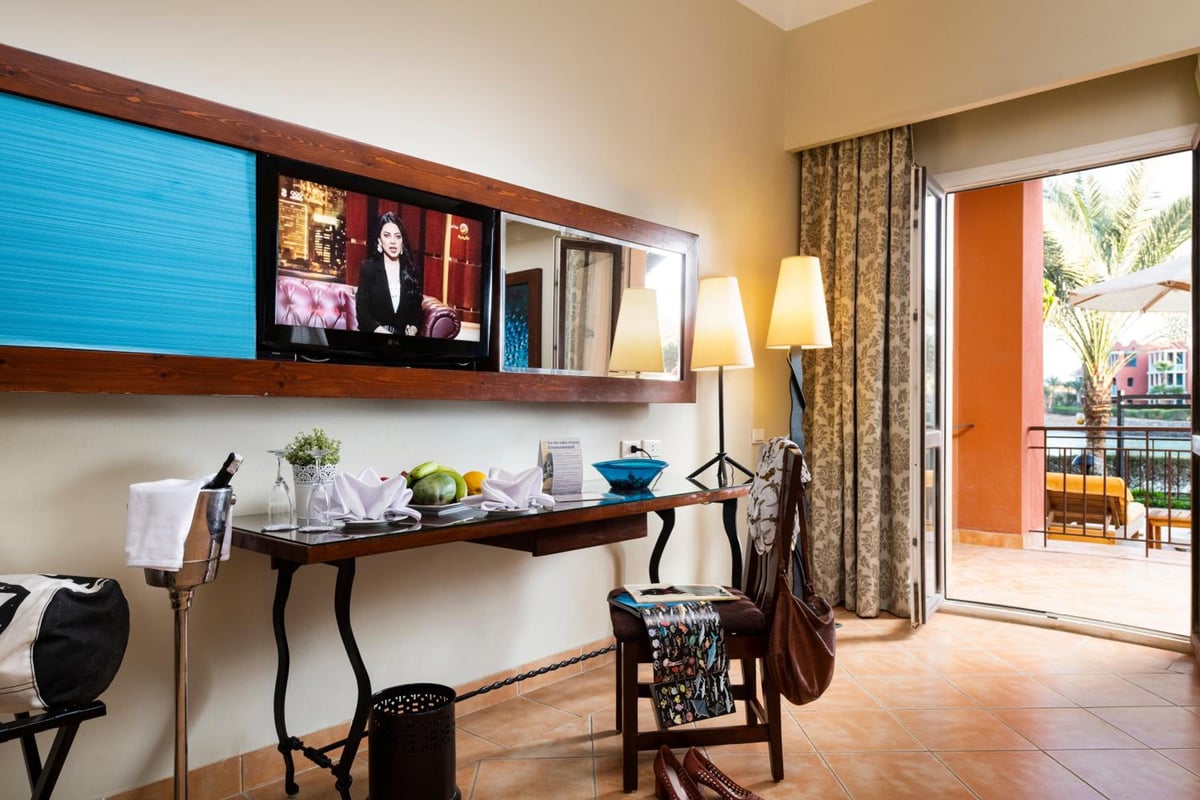 Three Corners Ocean View El Gouna (Adults Only) guest room with a desk and wall-mounted television.