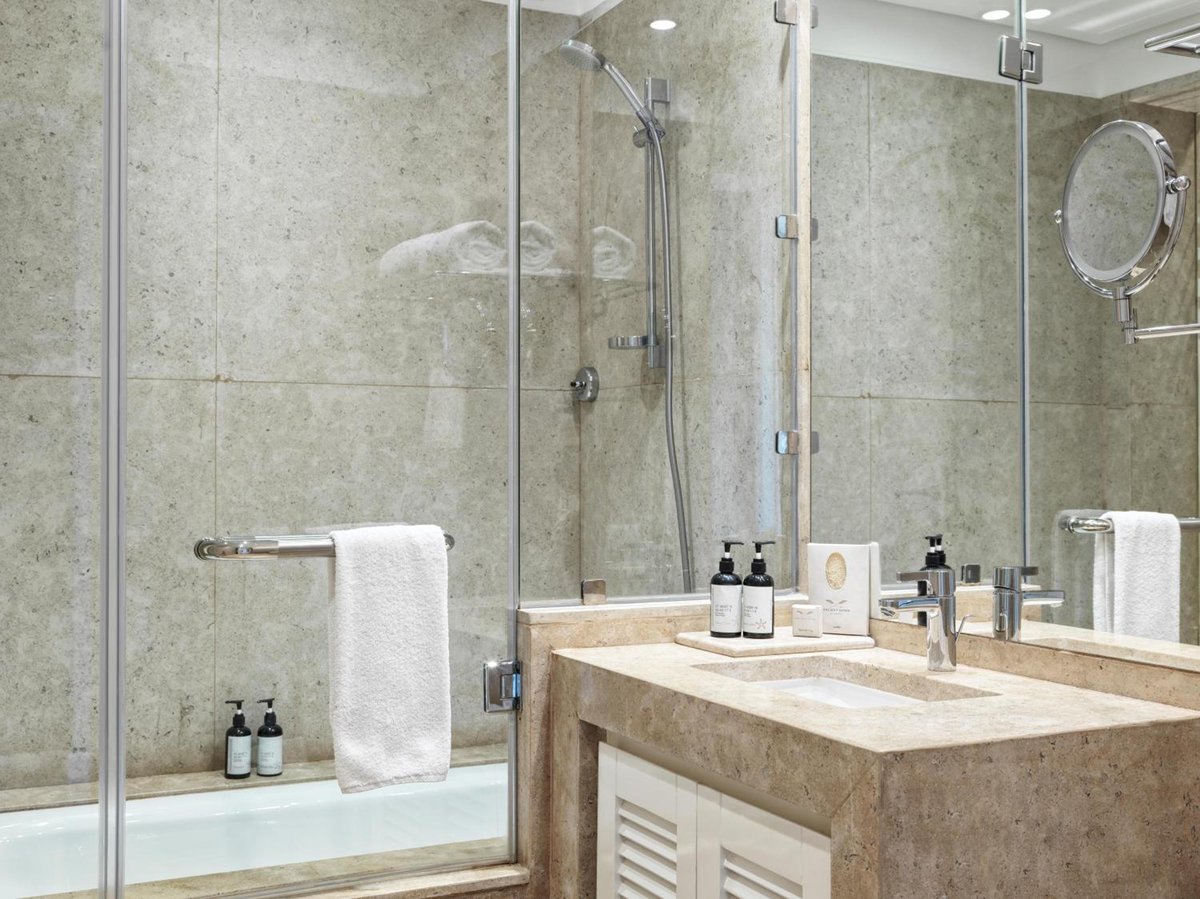 Ancient Sands Golf Resort bathroom with a glass-enclosed shower and stone vanity.