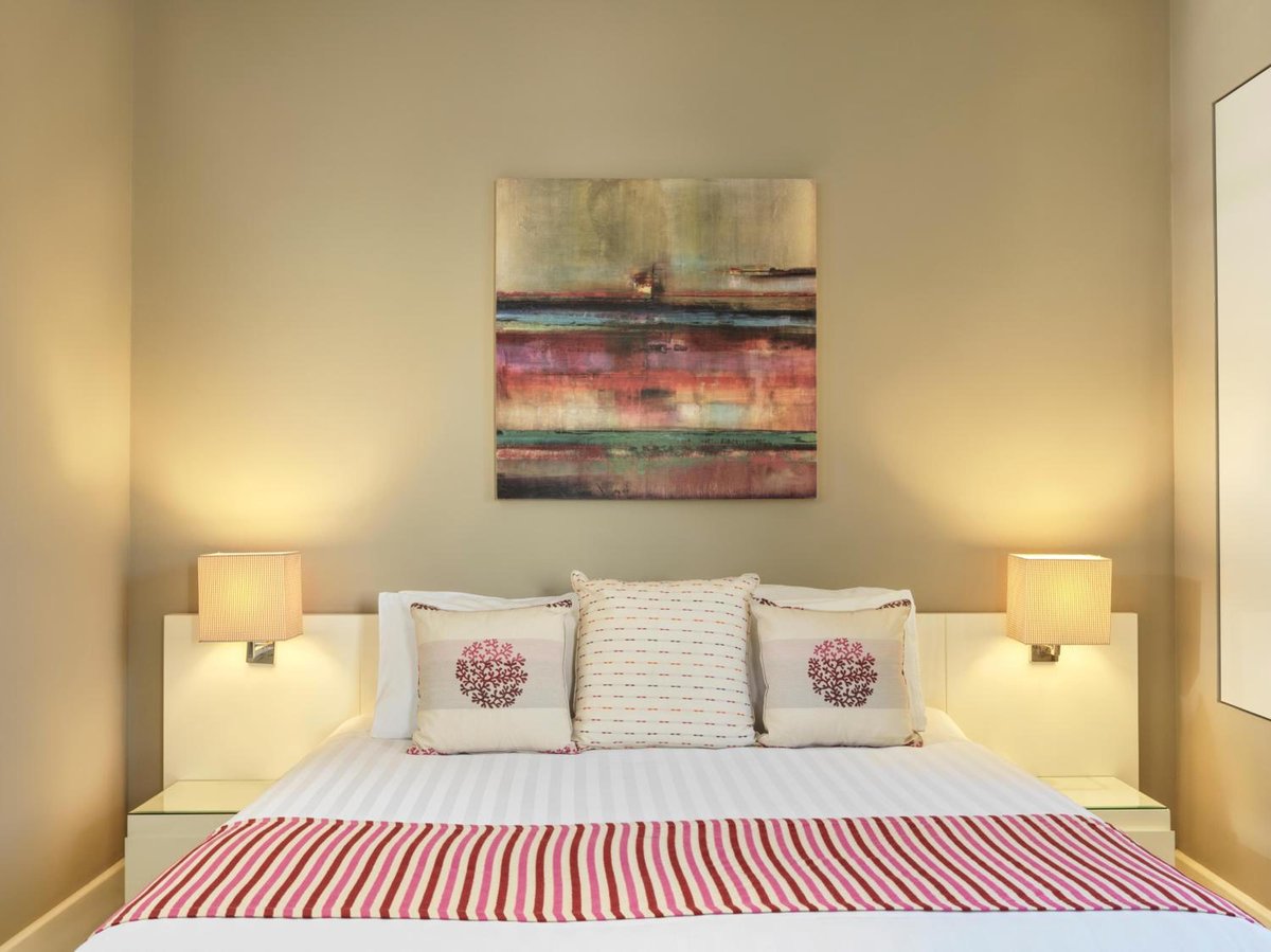 Ancient Sands Golf Resort bedroom with a striped bedspread and abstract wall art.
