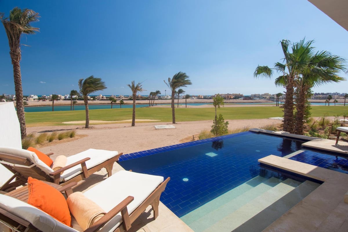 Ancient Sands Golf Resort pool with blue tiles and palm trees.