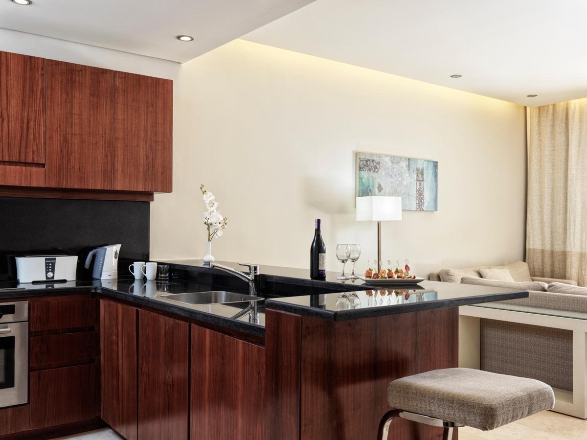 Ancient Sands Golf Resort kitchenette with wood cabinets and stone counters.