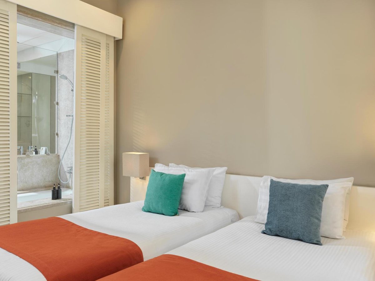 Ancient Sands Golf Resort twin bedroom with two single beds and a bathroom behind louvered doors.
