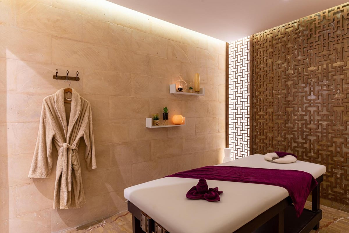 Ancient Sands Golf Resort spa treatment room with two massage tables and a patterned screen.