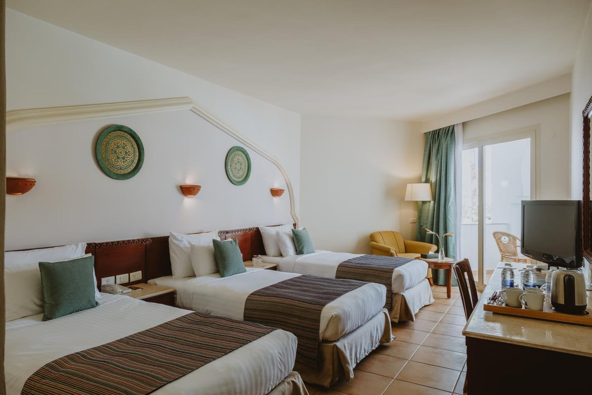 Baron Palms Resort (Adults Only) bedroom with three single beds and sliding glass doors.