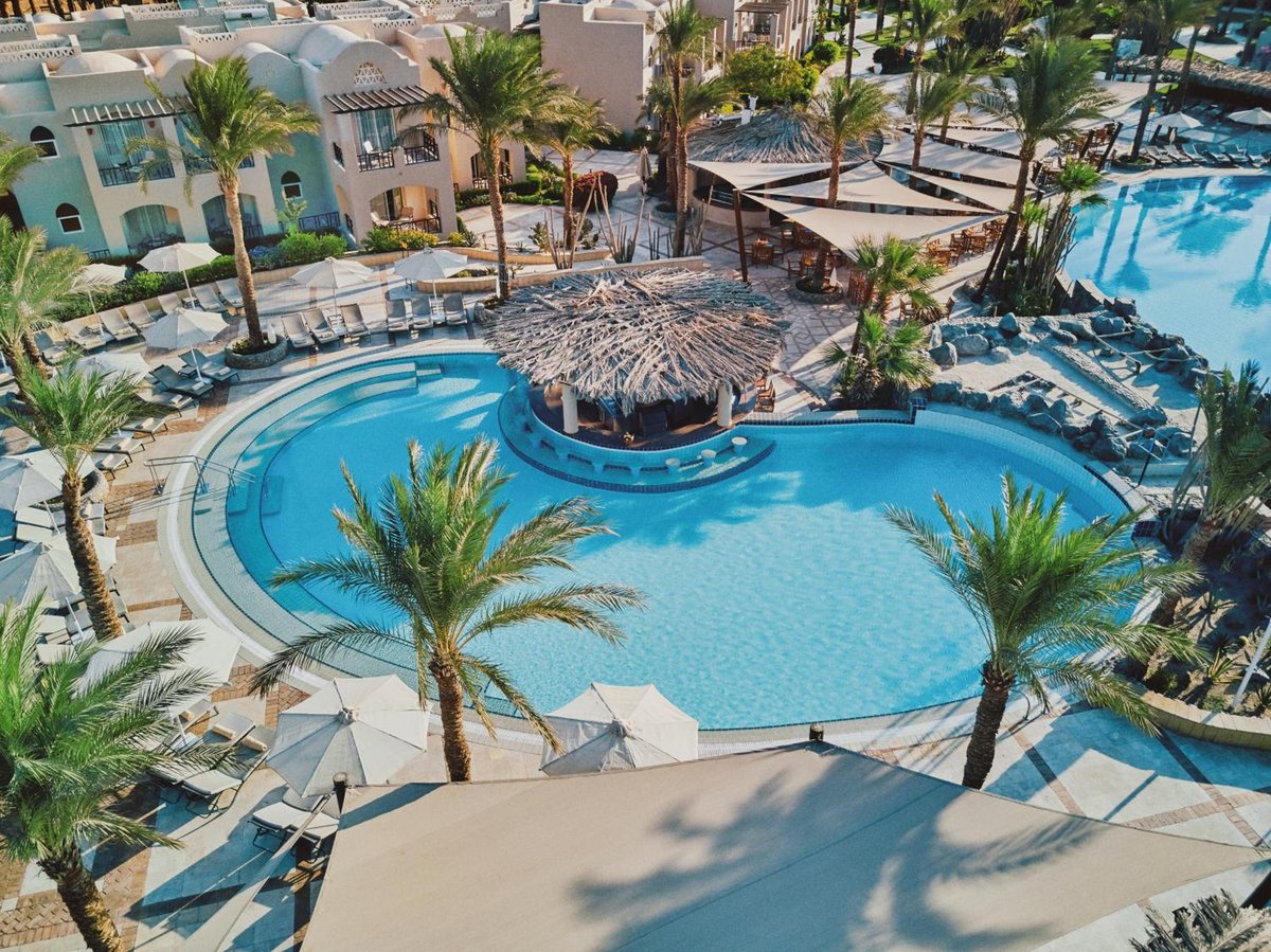 Iberotel Makadi Beach lagoon pool with a thatched-roof bar and curved edges.