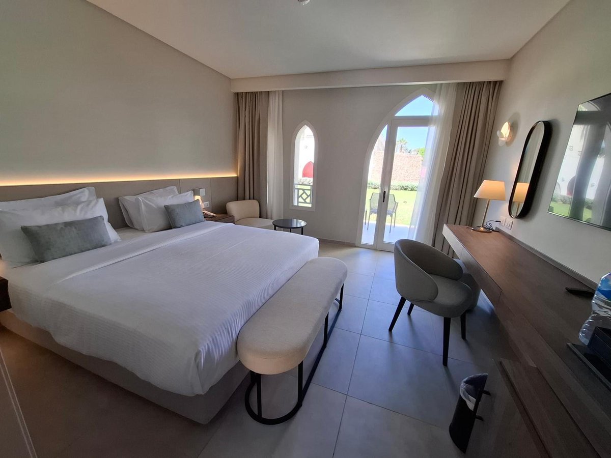Reef Oasis Beach Aqua Park Resort guest room with a bed and arched glass doors.