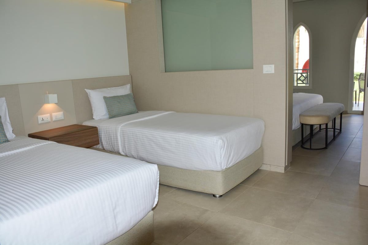 Reef Oasis Beach Aqua Park Resort twin bedroom with two beds and an arched doorway.