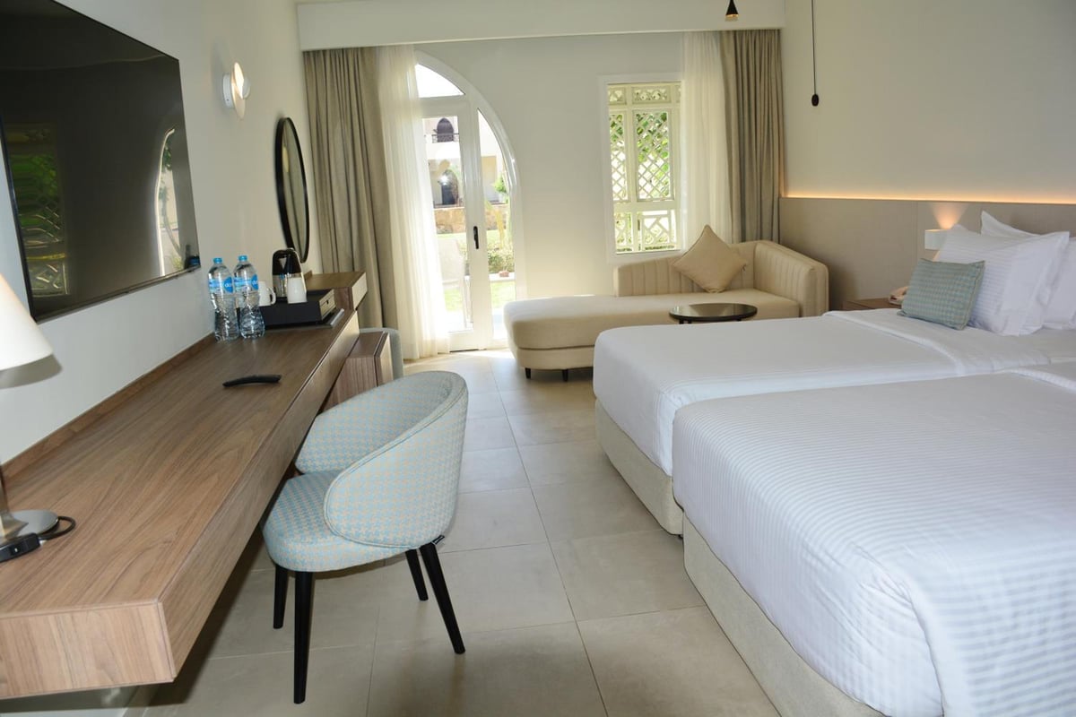 Reef Oasis Beach Aqua Park Resort guest room with a bed and sitting area.