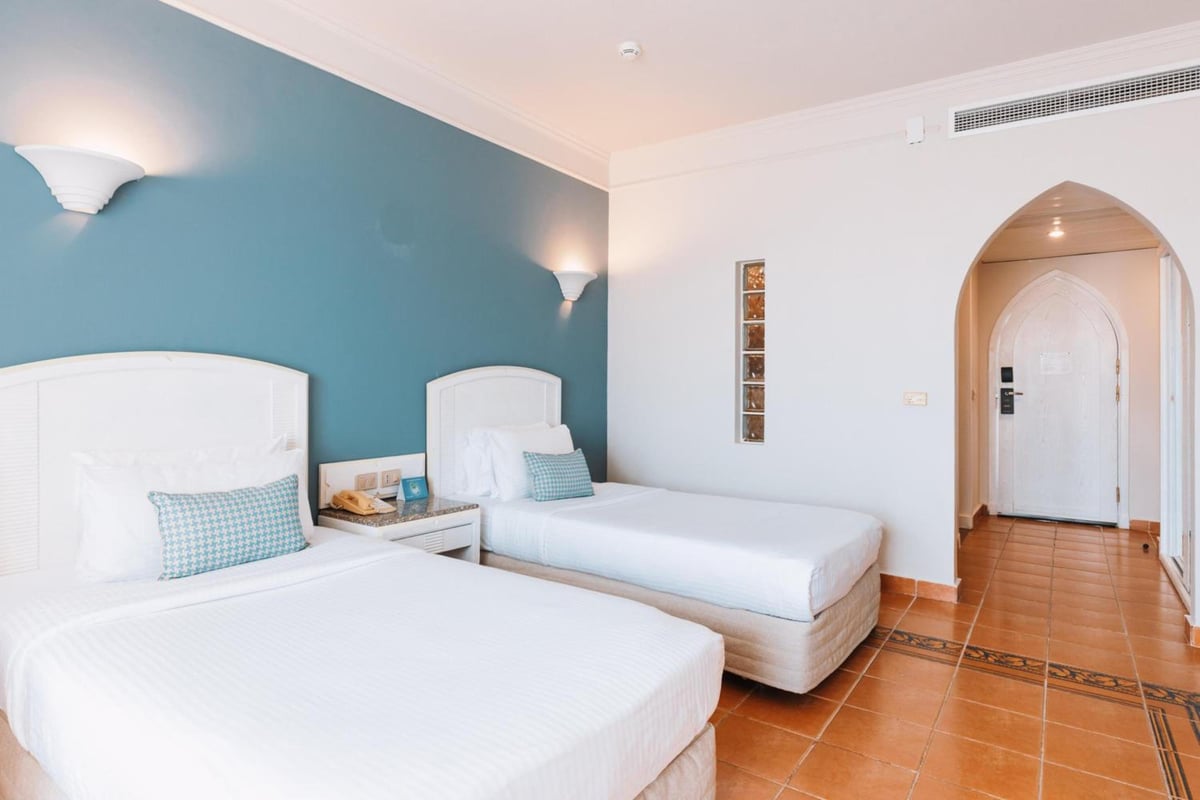 Reef Oasis Beach Aqua Park Resort twin bedroom with two beds and a teal accent wall.