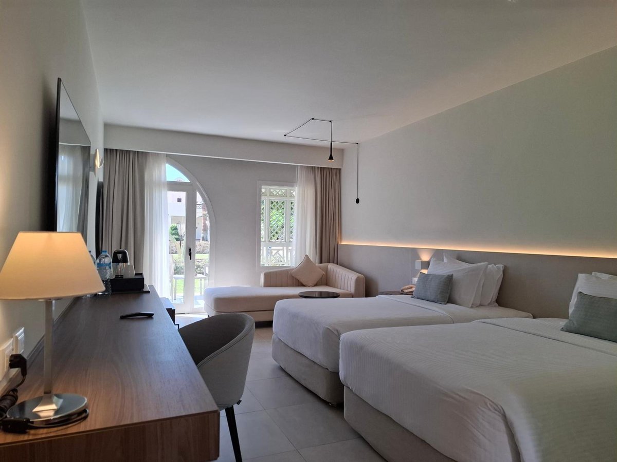 Reef Oasis Beach Aqua Park Resort guest room with two beds and an arched glass door.