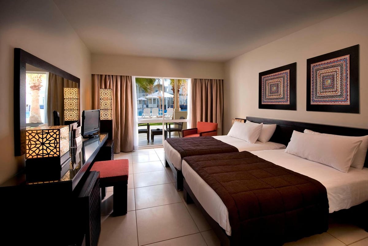 Reef Oasis Beach Aqua Park Resort bedroom with twin beds and sliding glass doors.
