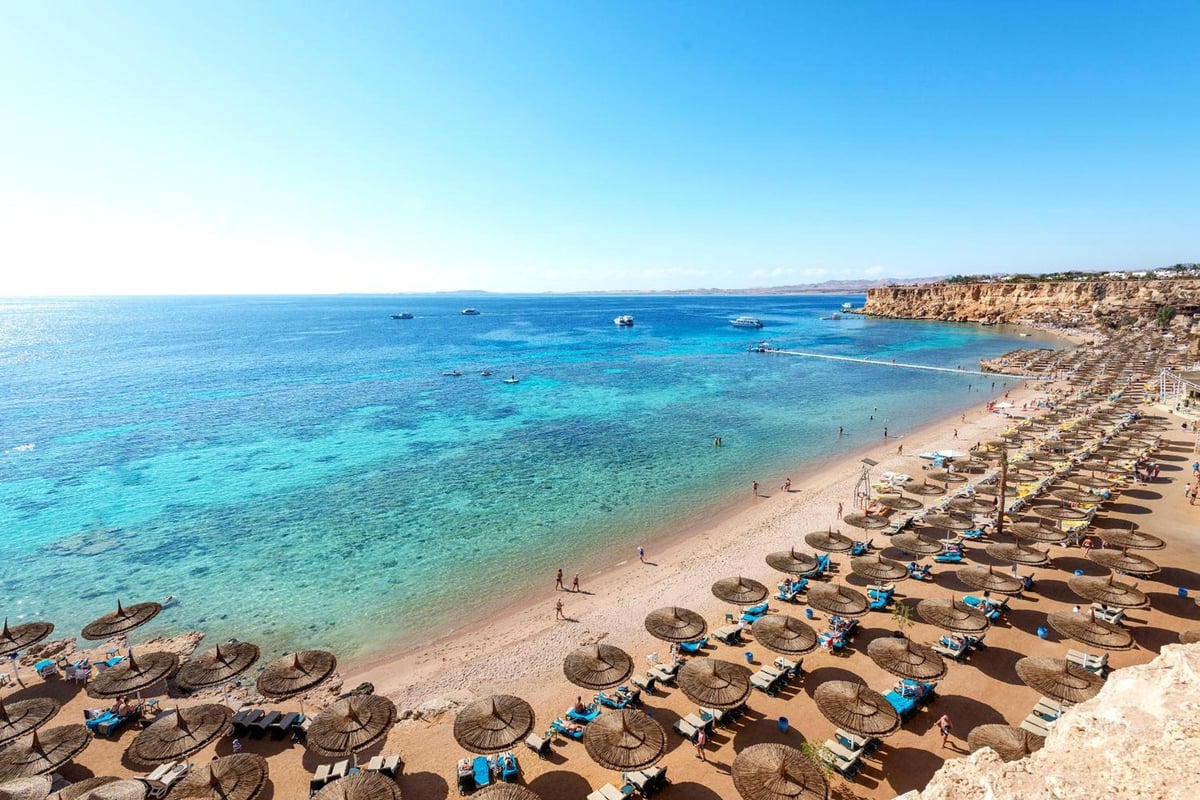 Reef Oasis Beach Aqua Park Resort beach with thatched parasols and turquoise water.