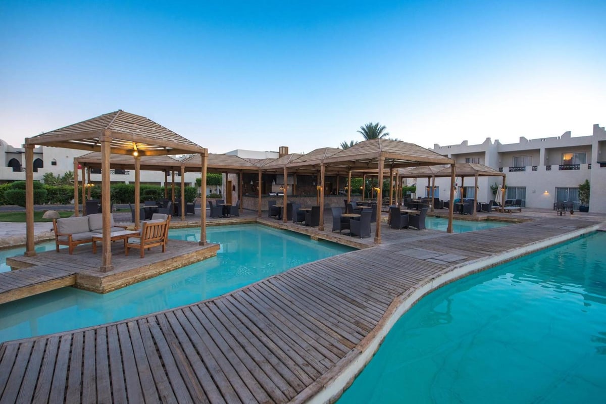 Reef Oasis Beach Aqua Park Resort pool deck with turquoise water and wooden pergolas.