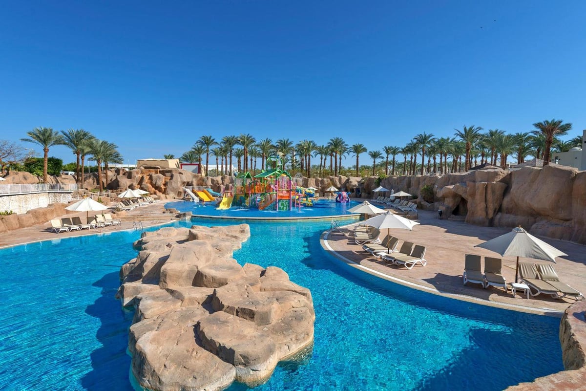 Reef Oasis Beach Aqua Park Resort aqua park pool with rock formations and colorful water slides.
