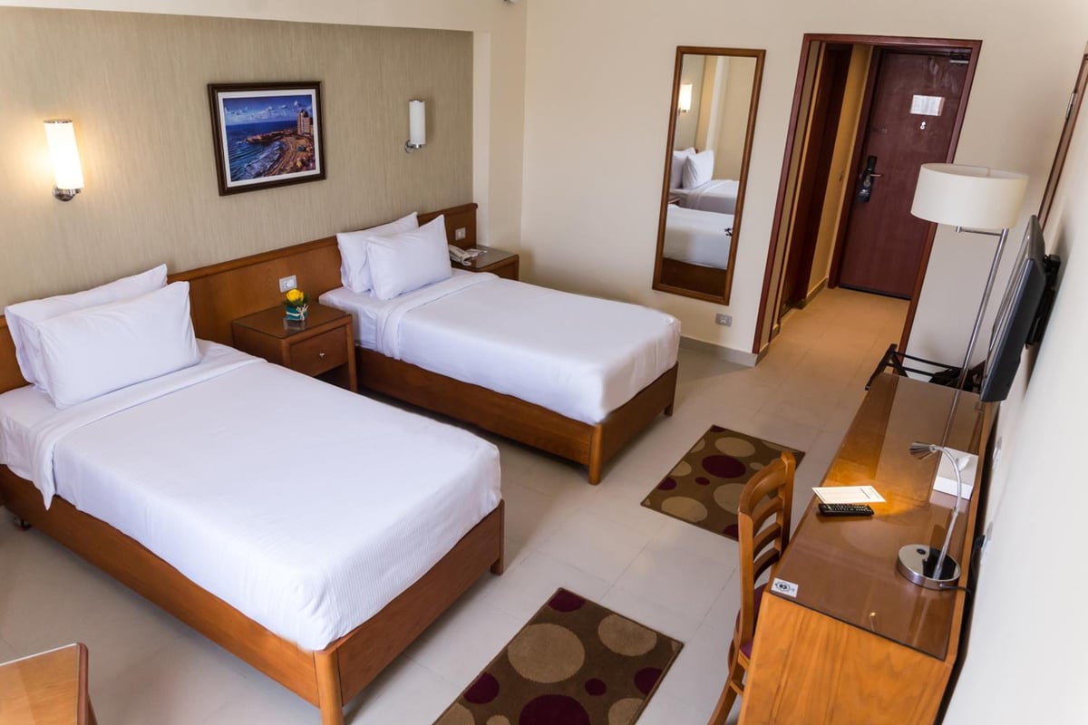 The Grand Plaza Hotel Smouha twin room with two beds and framed artwork.