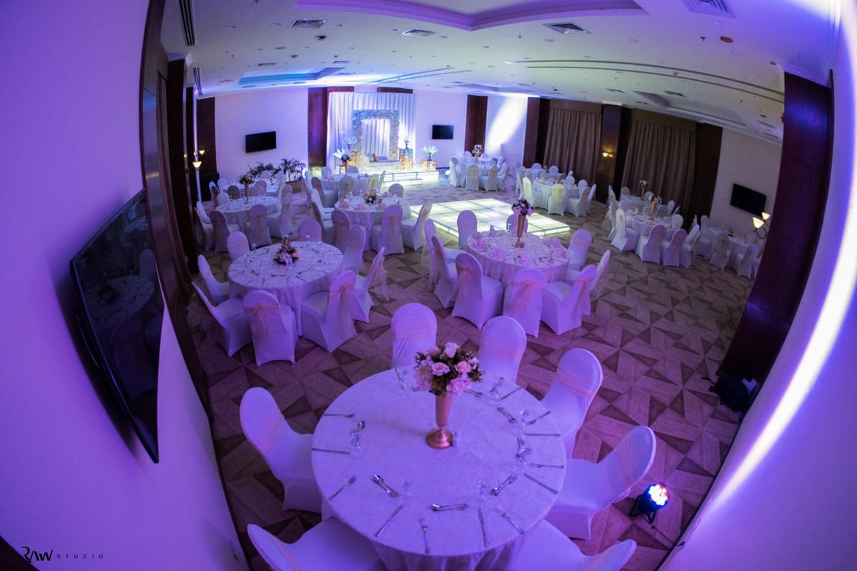 The Grand Plaza Hotel Smouha banquet hall with round tables and covered chairs.