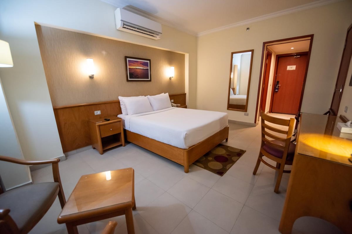 The Grand Plaza Hotel Smouha guest room with a bed and desk.