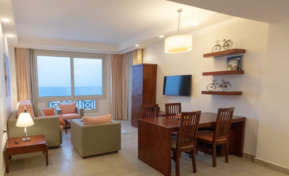 Oyster Bay Beach Suites living and dining room with a large window and wooden dining table.