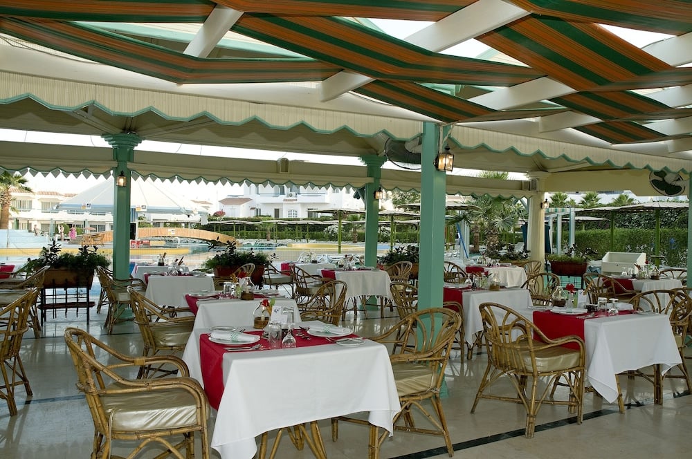 Dreams Beach - Sharm El Sheikh poolside restaurant with rattan chairs and striped fabric canopy.