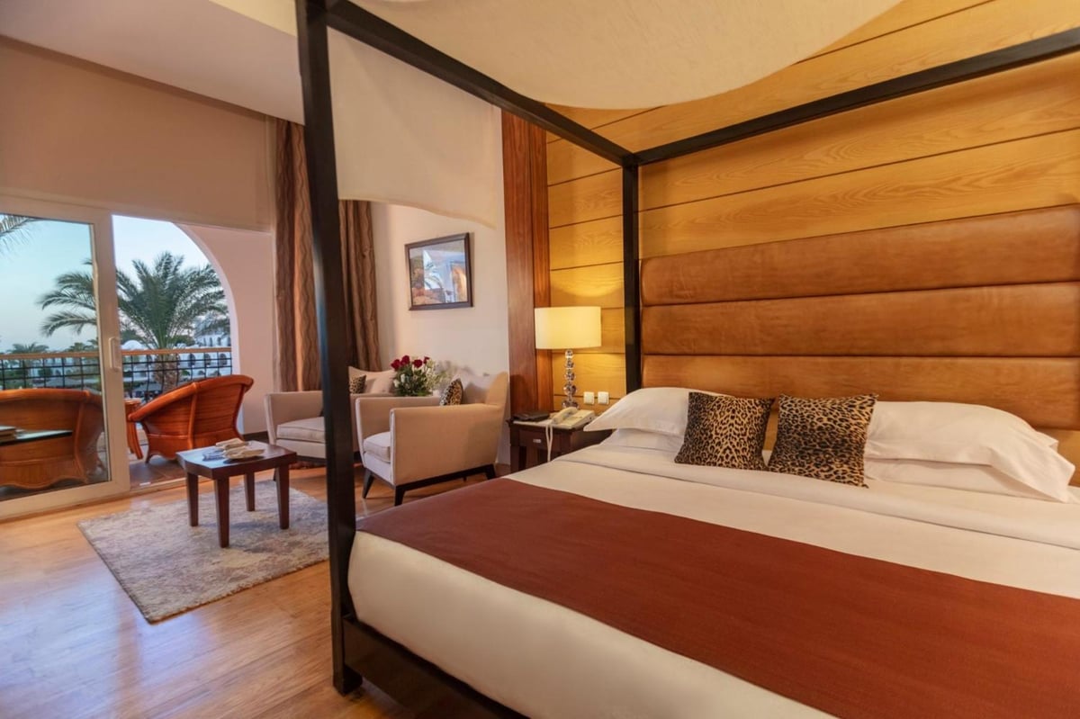 Royal Savoy Sharm El Sheikh bedroom with a four-poster bed and balcony doors.