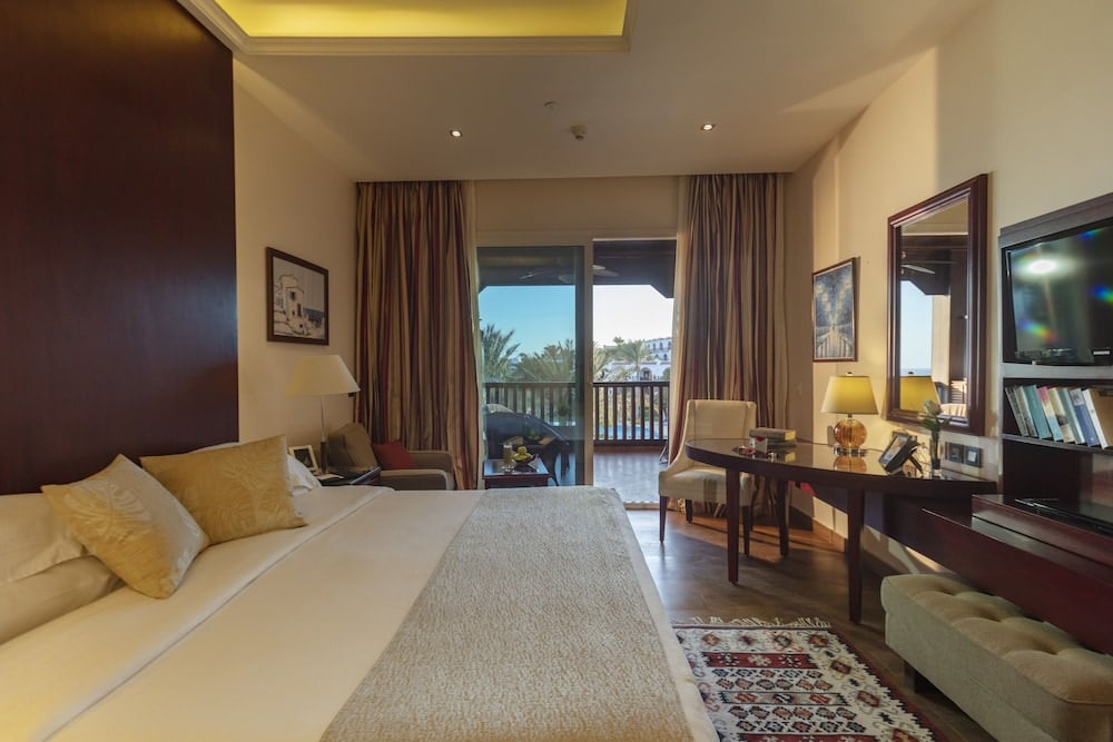 Royal Savoy Sharm El Sheikh guest bedroom with a large bed and balcony doors.