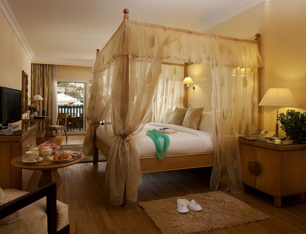 Royal Savoy Sharm El Sheikh bedroom with a sheer canopy bed and balcony doors.