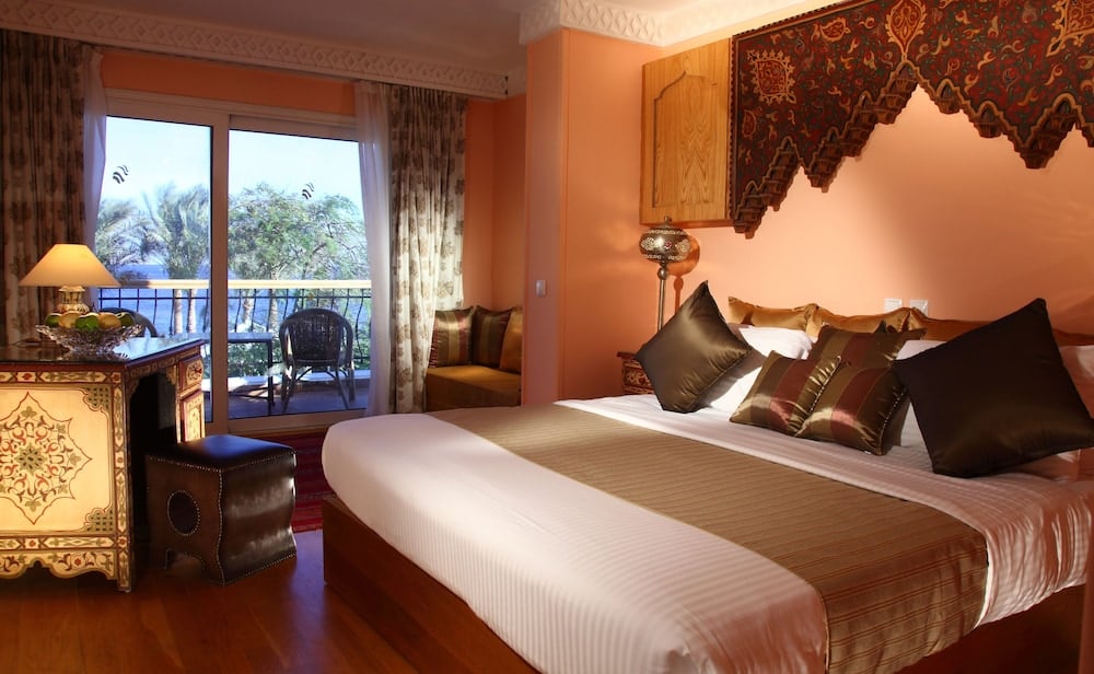 Royal Savoy Sharm El Sheikh bedroom with a large bed and balcony doors.