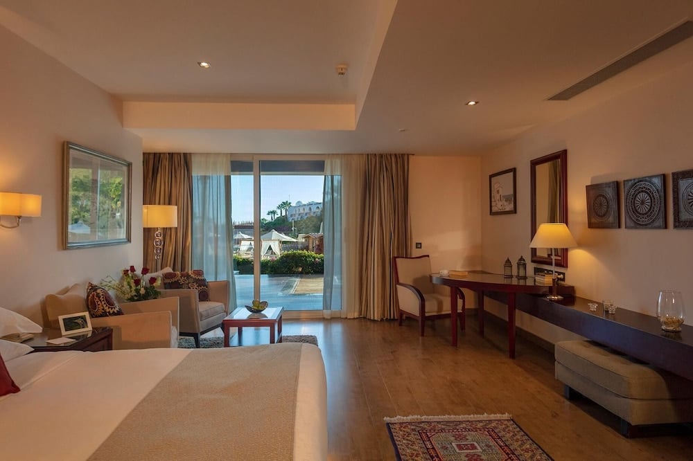 Royal Savoy Sharm El Sheikh guest room with a sitting area and sliding glass doors.