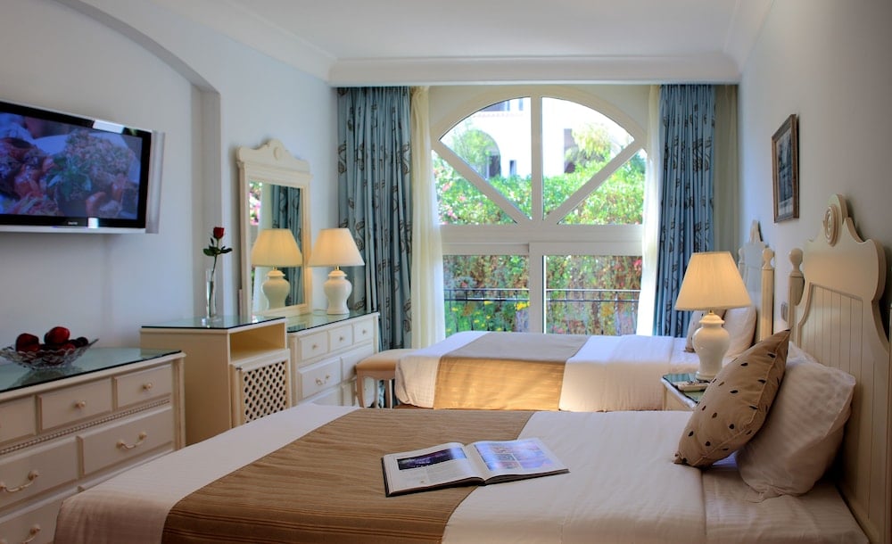 Royal Savoy Sharm El Sheikh guest room with twin beds and an arched window.
