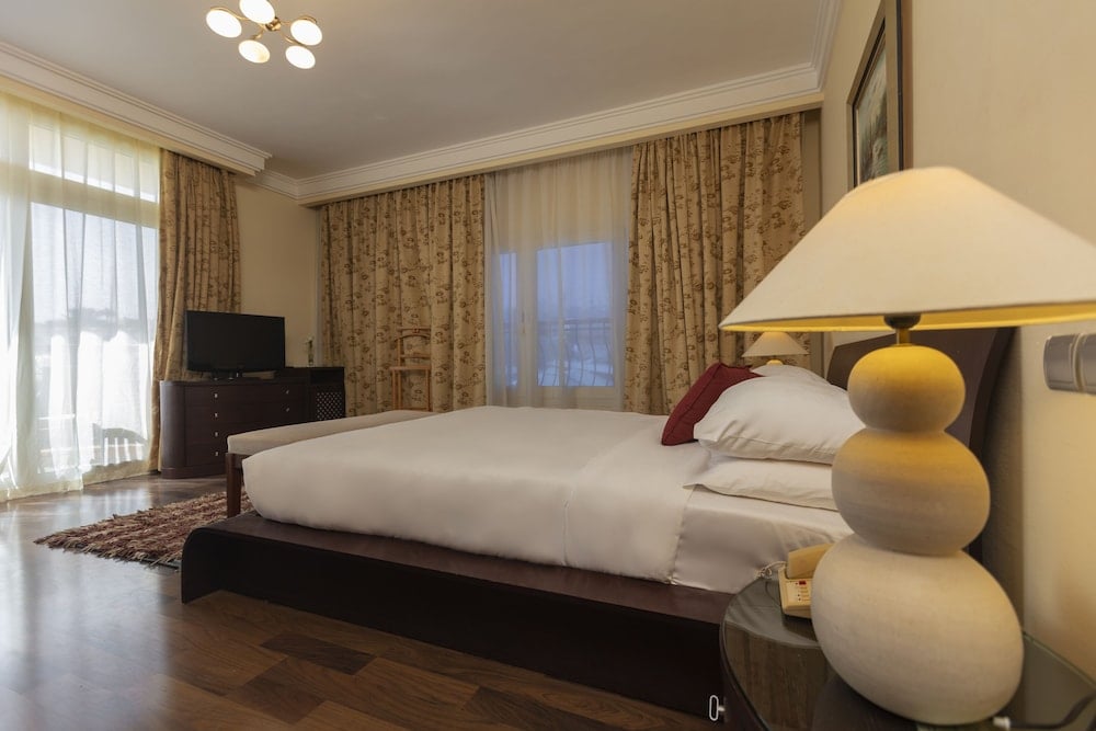 Royal Savoy Sharm El Sheikh bedroom with a large bed and patterned curtains.