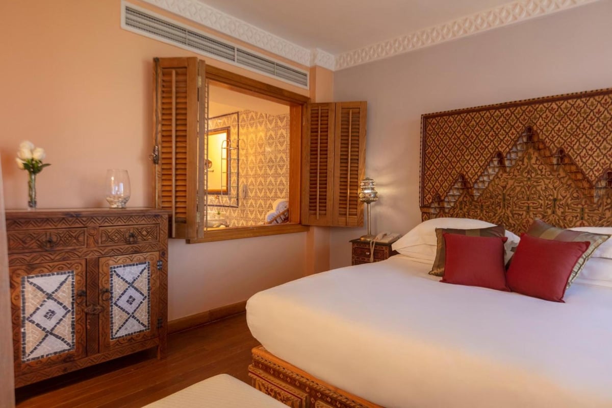 Royal Savoy Sharm El Sheikh bedroom with a carved headboard and open wooden shutters.