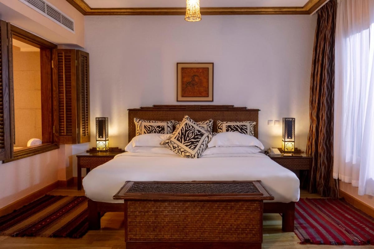 Royal Savoy Sharm El Sheikh bedroom with a carved headboard and decorative pillows.