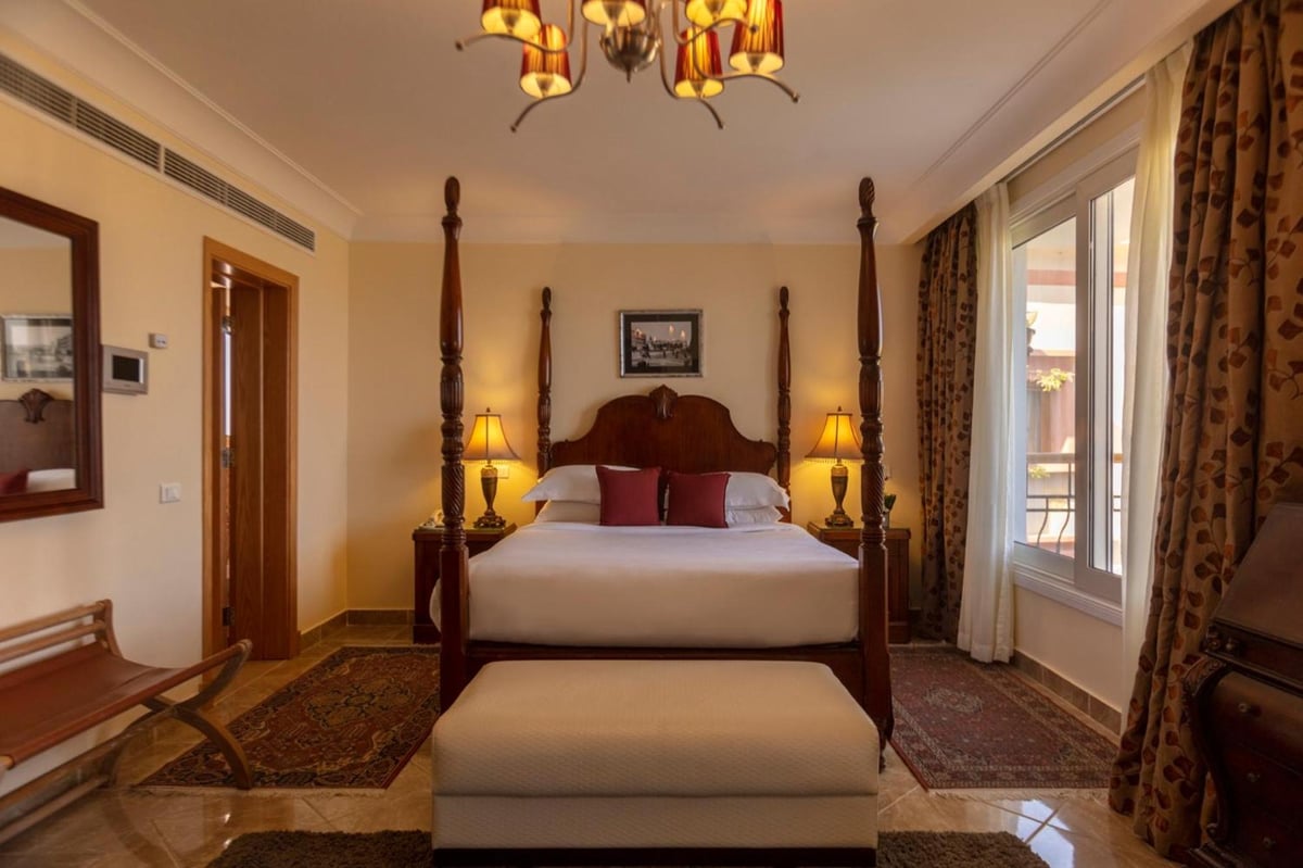 Royal Savoy Sharm El Sheikh bedroom with a four-poster bed and balcony doors.