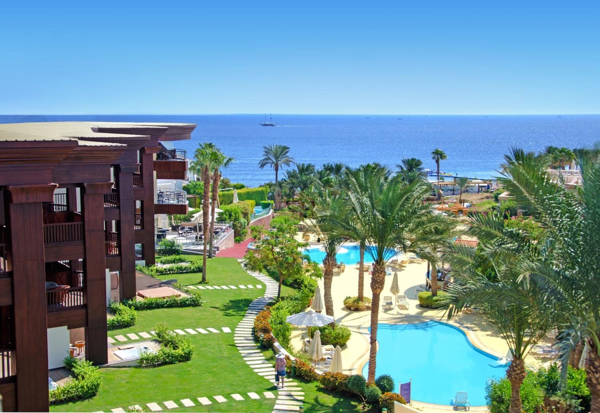 Royal Savoy Sharm El Sheikh resort grounds with a swimming pool and palm trees.