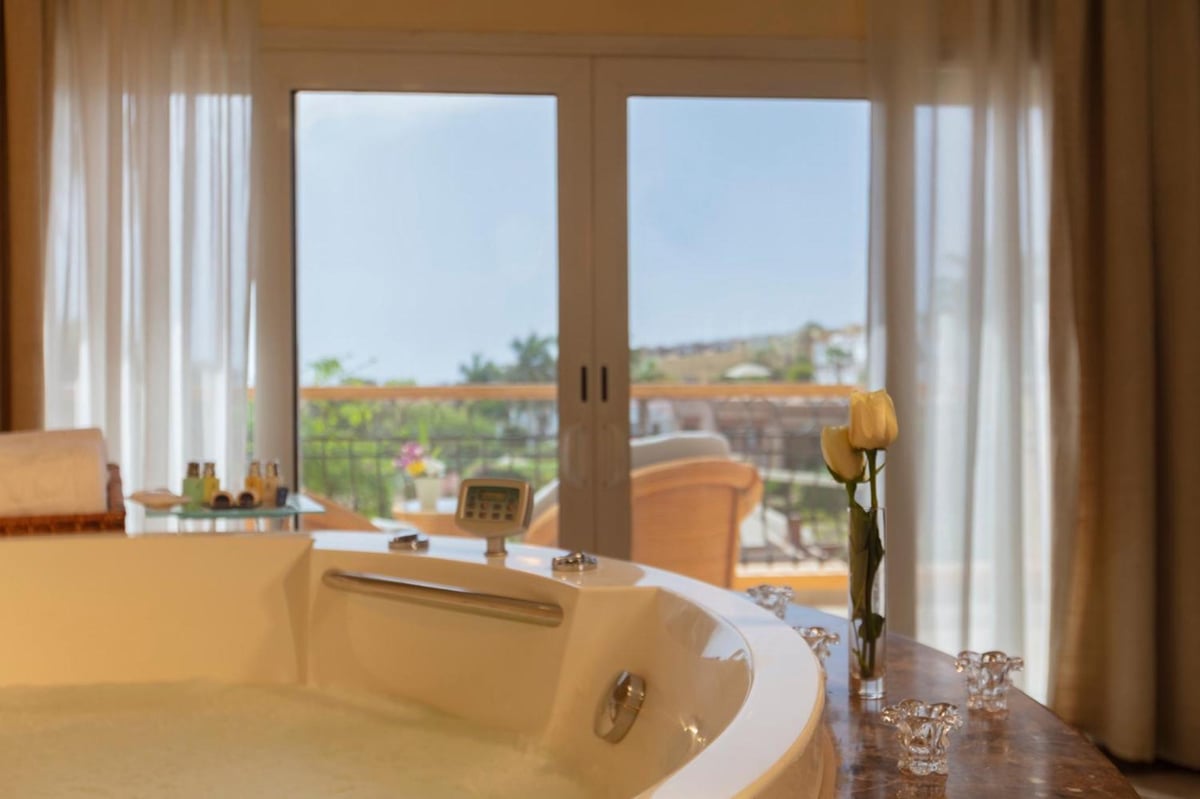 Royal Savoy Sharm El Sheikh bathroom with a curved bathtub and balcony doors.