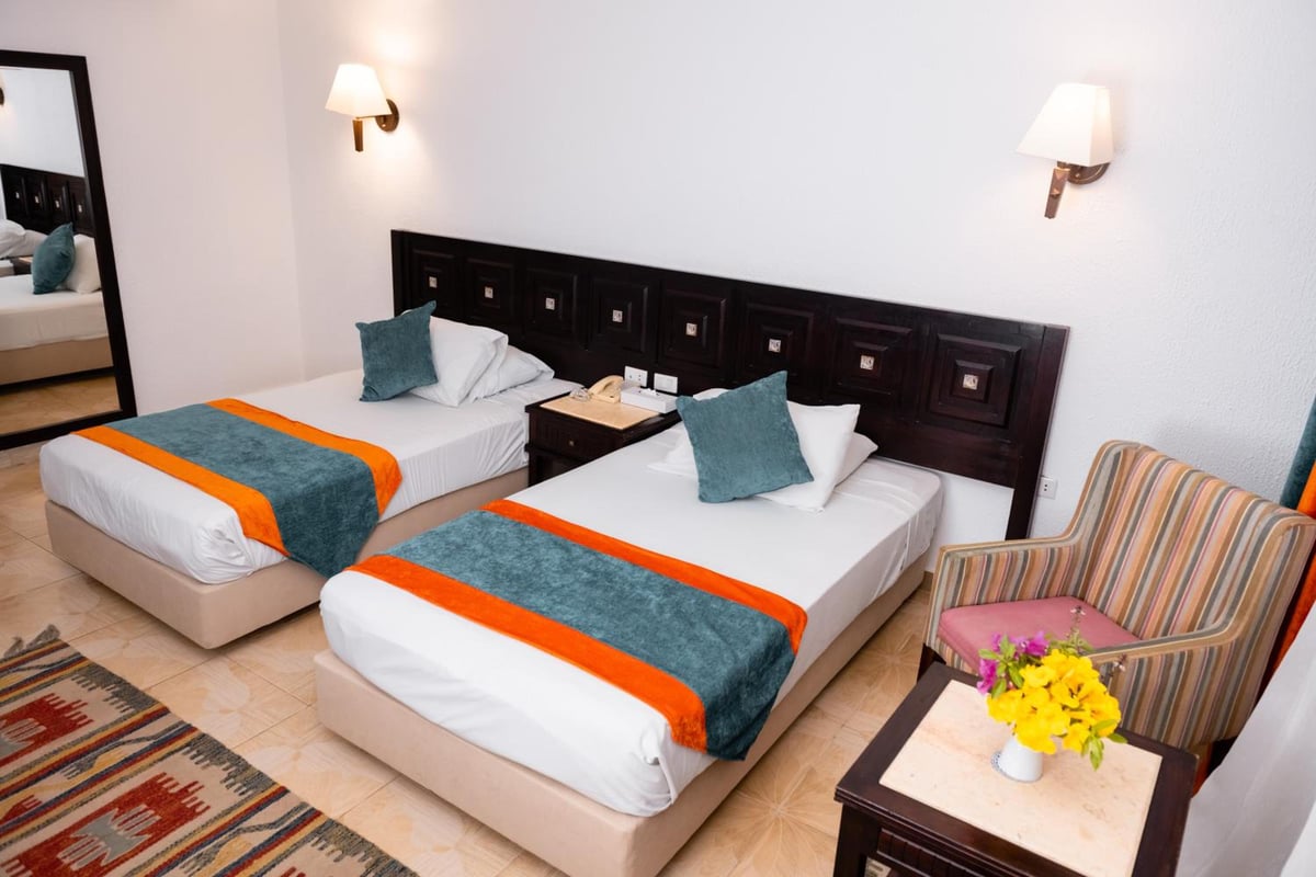 Turquoise Beach Hotel twin bedroom with two beds and a dark wood headboard.