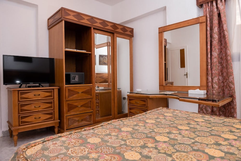 Turquoise Beach Hotel guest room with a patterned bedspread and wooden wardrobe.