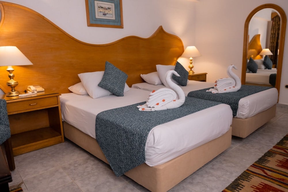 Turquoise Beach Hotel twin bedroom with two beds and a curved wooden headboard.
