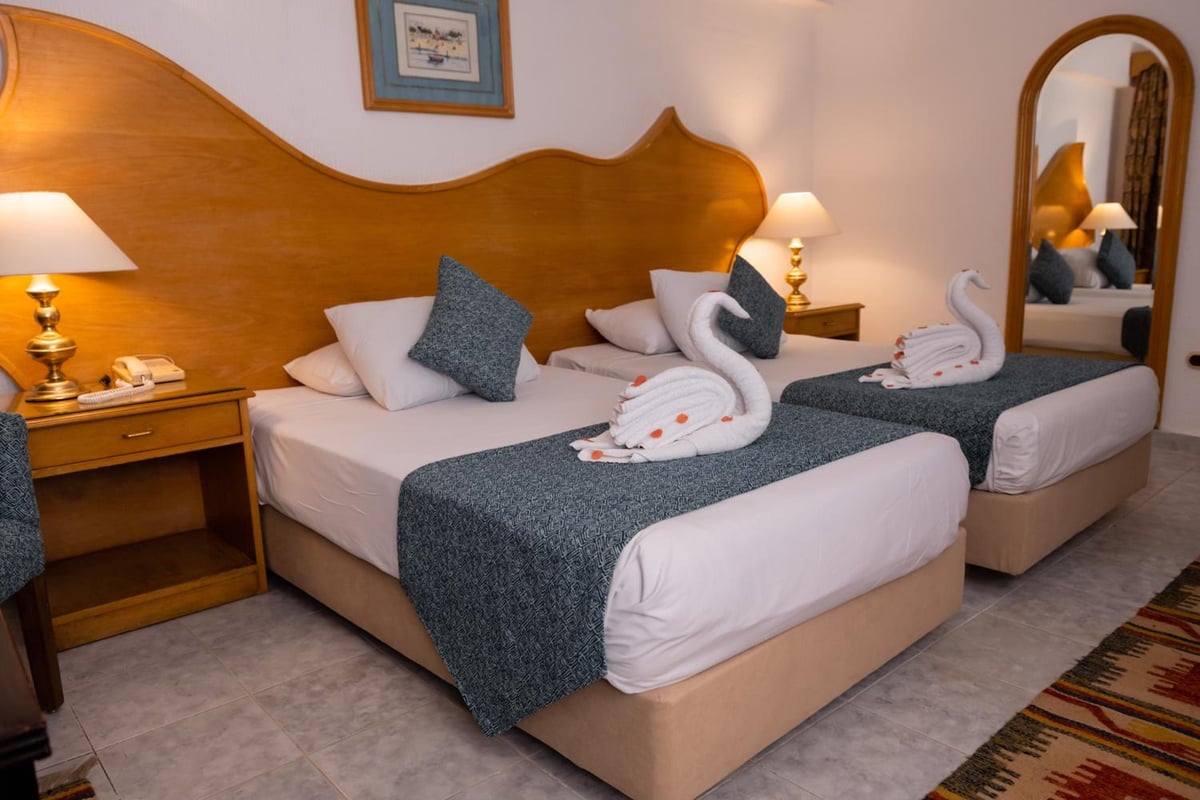 Turquoise Beach Hotel twin room with two beds and a curved wooden headboard.