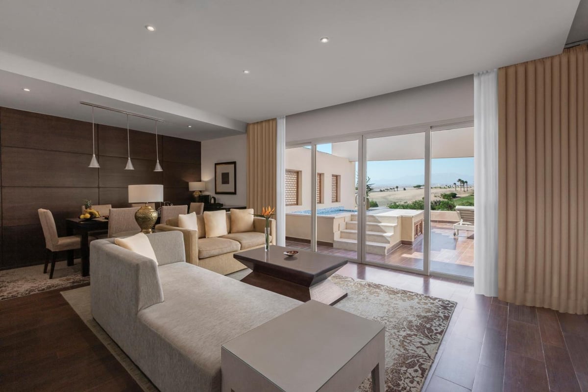 Steigenberger Makadi (Adults Friendly 16+) suite living room with a sectional sofa and sliding glass doors.