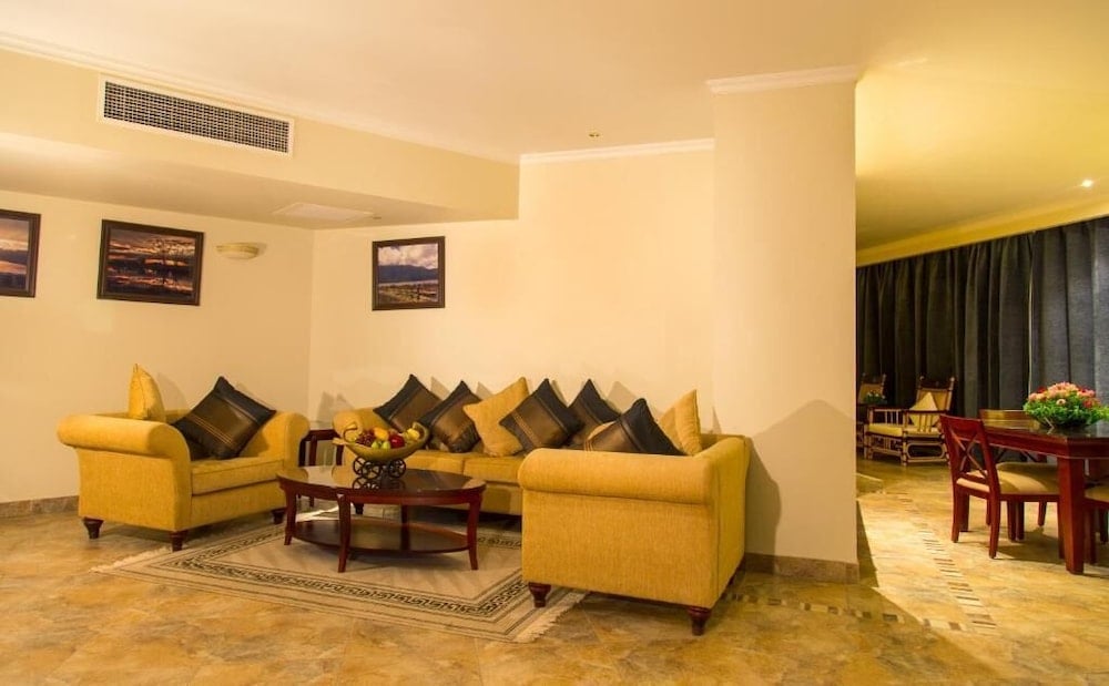 Jolie Ville Hotel & Spa Kings Island Luxor living room with yellow sofas and an adjoining dining area.